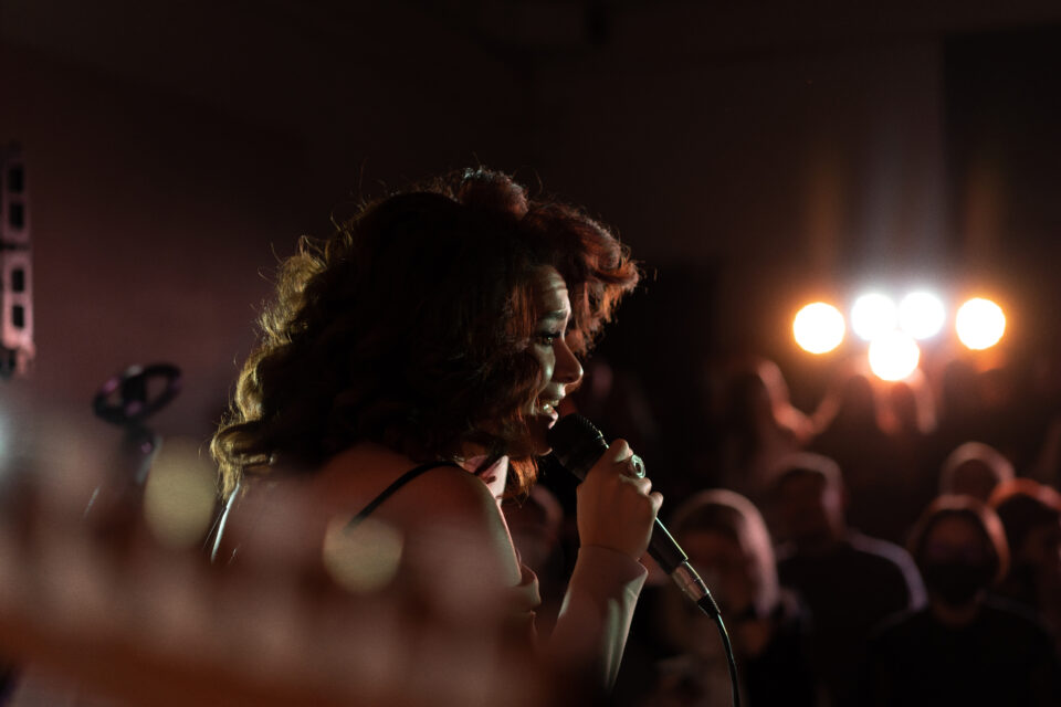 young beautiful woman singer on stage singing into microphone